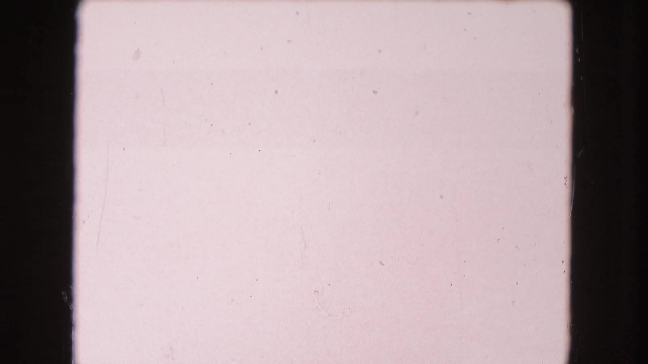 Mostly pale pink film frame with black borders, light scratches, and minimal visible subject detail.