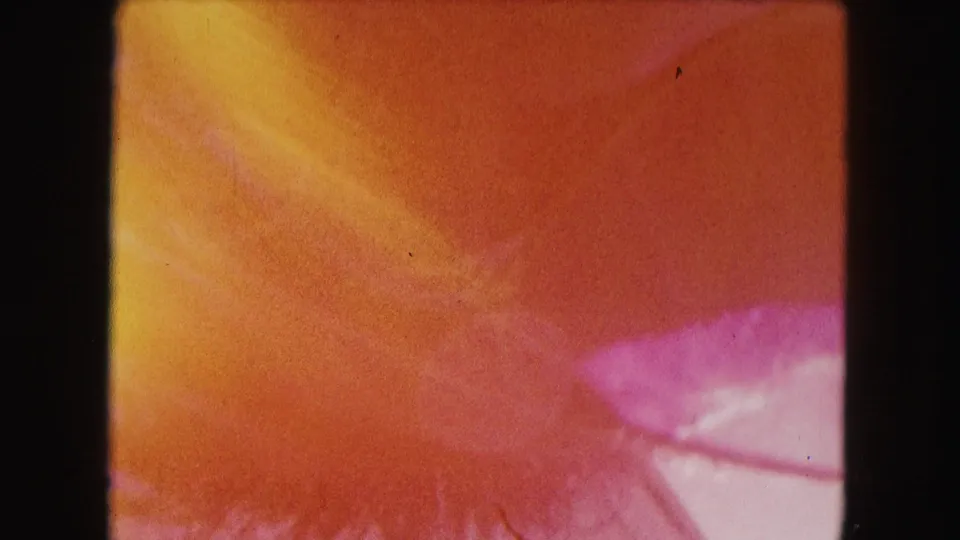 1960 Miami 8mm close-up where the spinning cup becomes a warm red-orange and pink blur against black film borders.