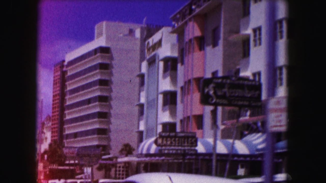 Miami hotel street with multi-story buildings, awnings, and visible business signs.