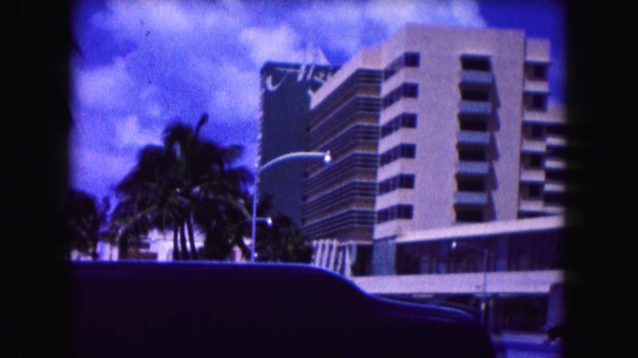 Palm trees and modern hotel buildings seen from a moving car.