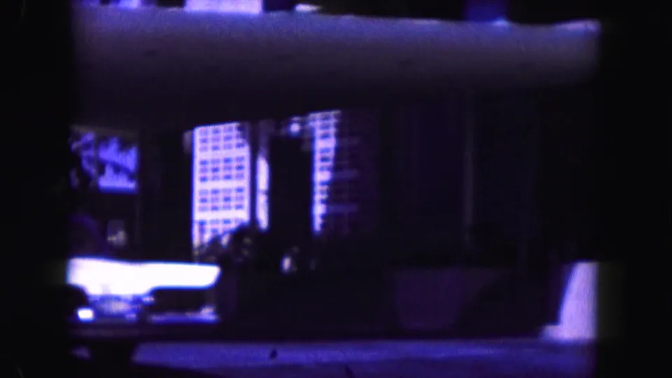 1960 Miami 8mm frame with a dim, soft view of building windows and street scenery, heavily shifted toward blue-purple tones.