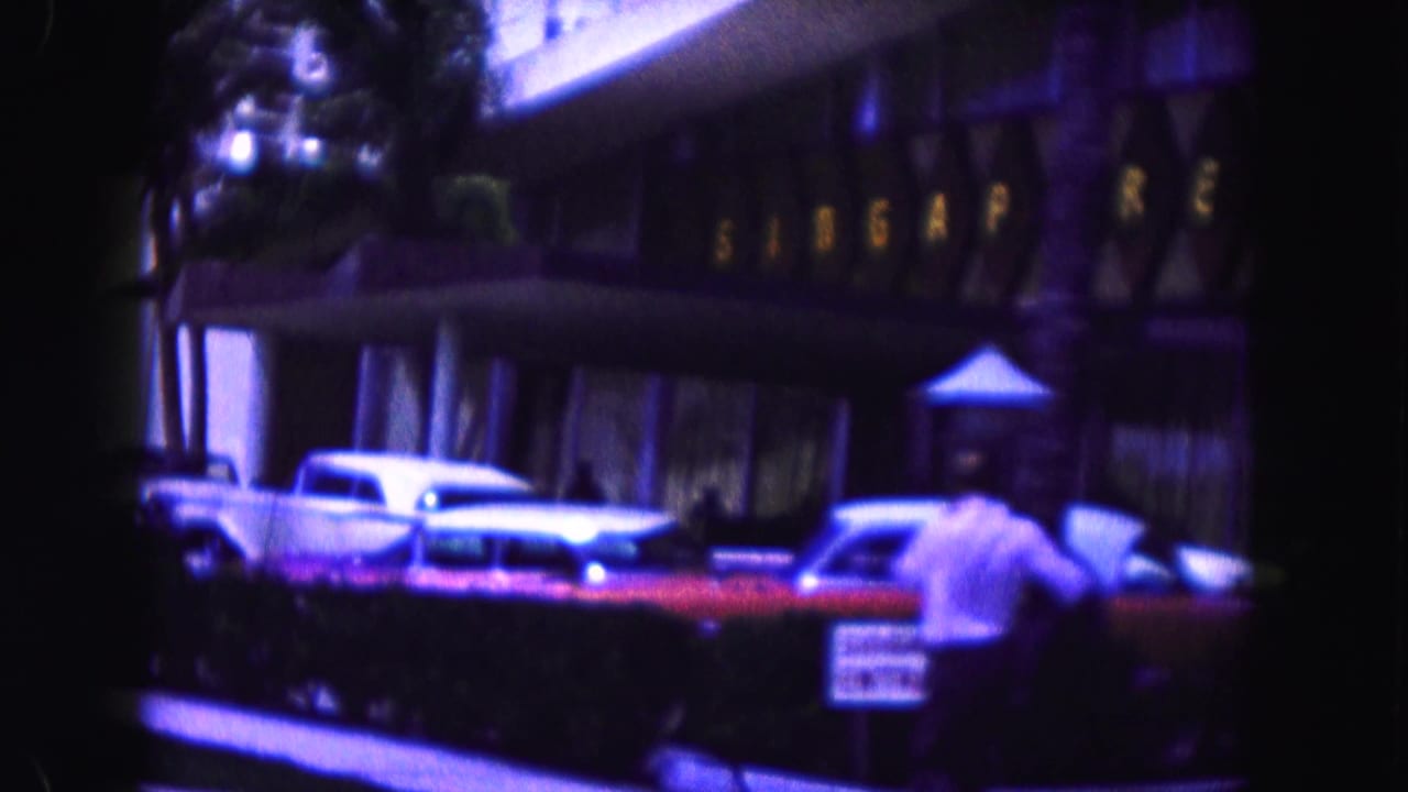 White classic car parked before a hotel entrance with Singapore lettering above.