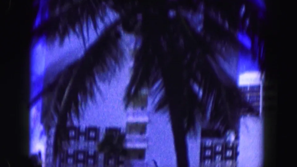 1960 Miami-area 8mm frame with palm trees, building windows, and a Bal Harbour city limit sign partly visible.