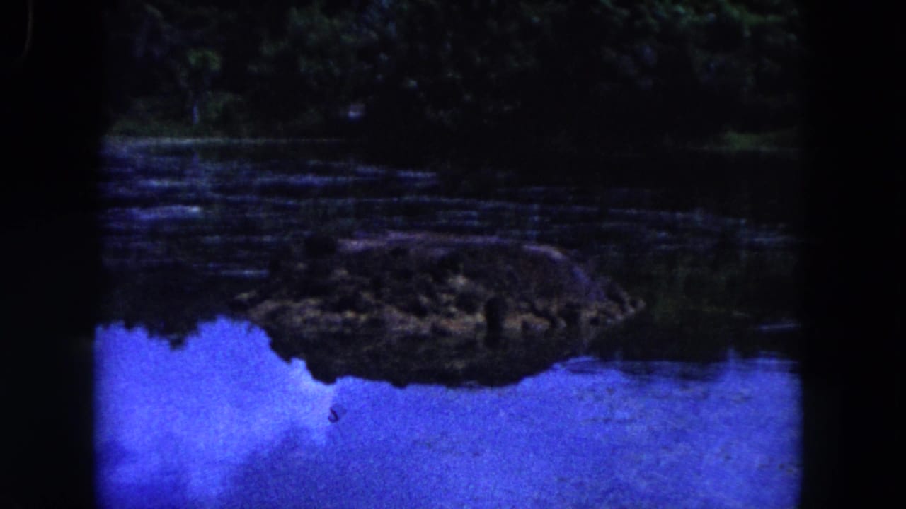 Blue-toned lagoon water with a dark rock formation reflected near the shore.