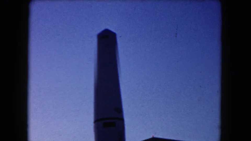 Close 1960 Miami frame of the rocket replica's upper section silhouetted against a blue twilight-looking sky.