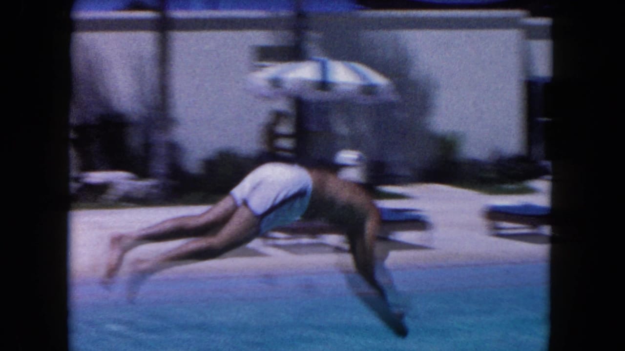 Man diving forward into a blue outdoor swimming pool.
