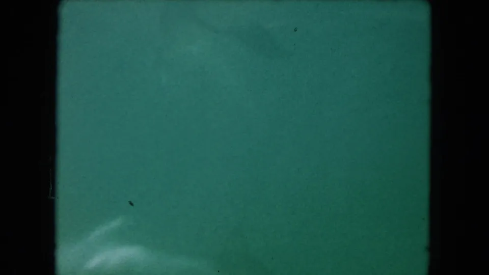 Final 1960 Miami underwater pool frame with hazy green-blue water, pale movement near the bottom, and 8mm speckling.