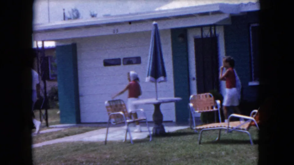 The final 1960 Miami frame shows a child near a closed umbrella and an adult at the right edge outside the house.