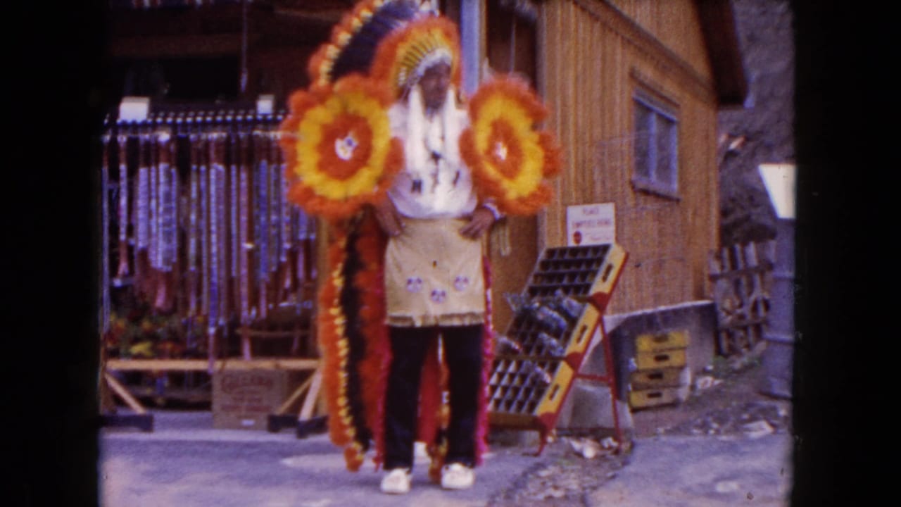 Costumed man stands in front of a storefront beside display racks and hanging items.