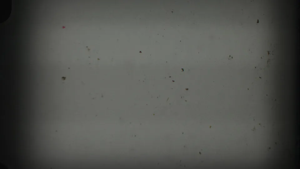 Dark, underexposed 8mm leader-like frame from a 1960 Florida home movie, showing dust, specks, and gate shadow.