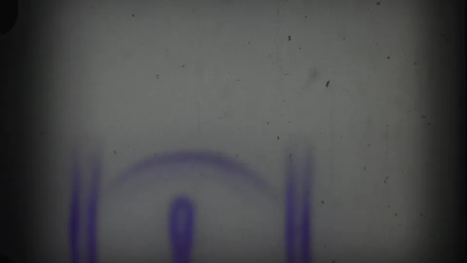 Soft, faded 8mm frame with a blurred purple edge marking and visible dust during the reel opening.