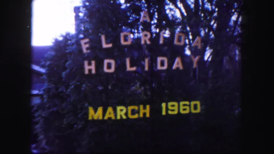 1960 Florida home-movie title card reading A Florida Holiday March 1960, seen against dark trees and foliage.
