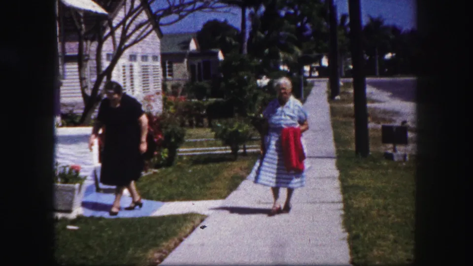 The final frame shows the two women near the sidewalk in a sunny 1960 Tampa neighborhood, with houses, lawn, and palms behind them.