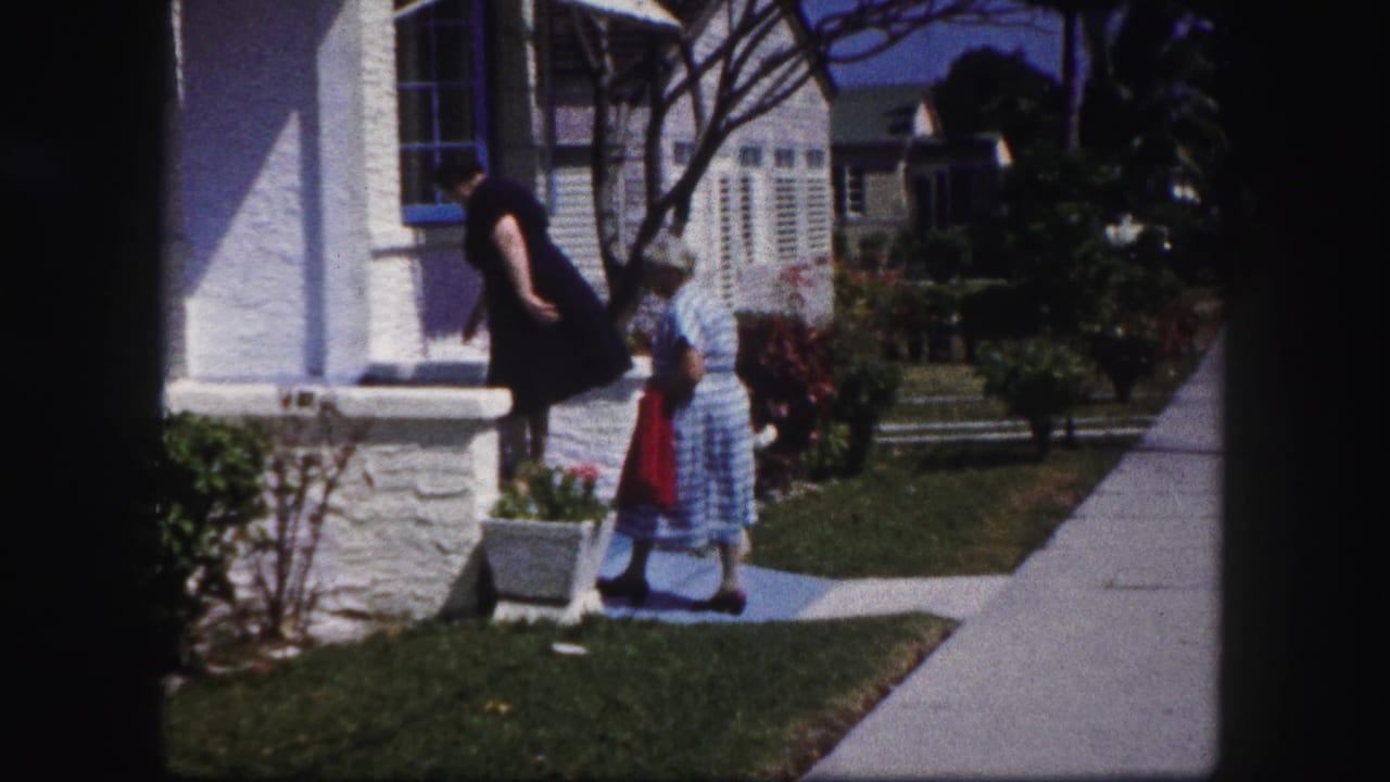 In Tampa, Florida, 1960 home-movie footage, two women appear near a white stucco porch with potted plants and a concrete walkway.