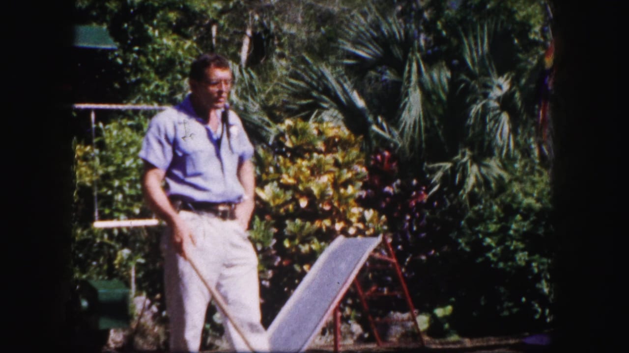 The man remains near the ramp in the Tampa garden, framed by palms and shrubs in sunlit 8mm color footage.