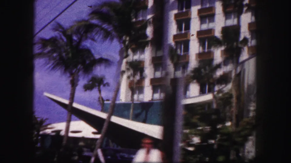 1960 Tampa hotel exterior showing palms, balconies, a vertical pole, and a sail-like canopy near the base.