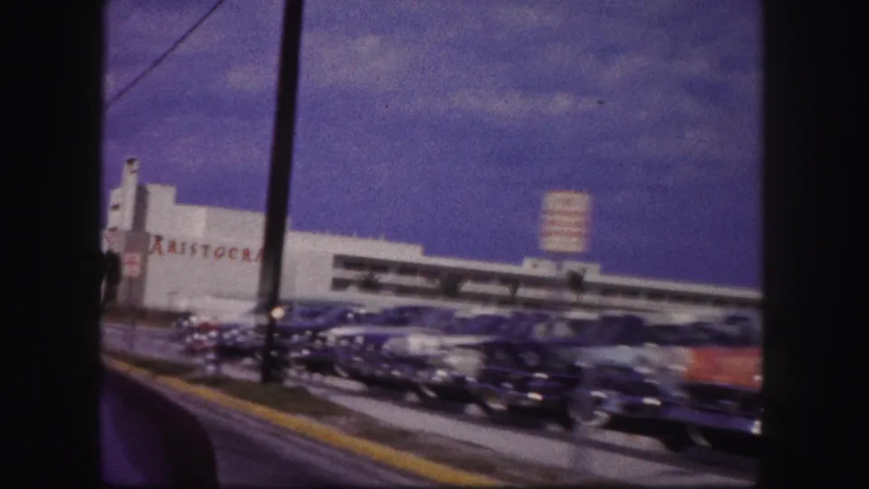 The 1960 Tampa footage shows cars packed in front of the white Aristocrat building, with a street pole and blue sky visible.