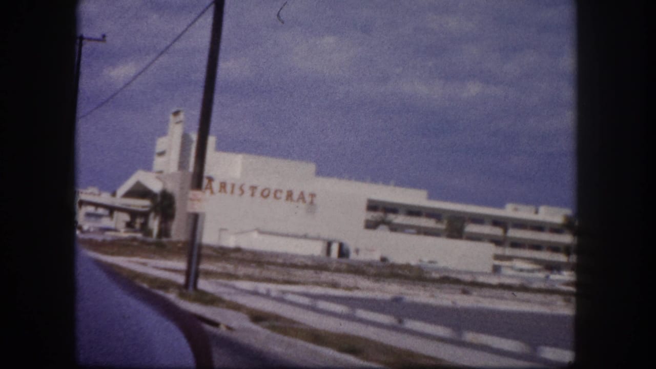 1960 Tampa drive-by frame showing a white roadside building with red ARISTOCRAT lettering, utility poles, and road edge.