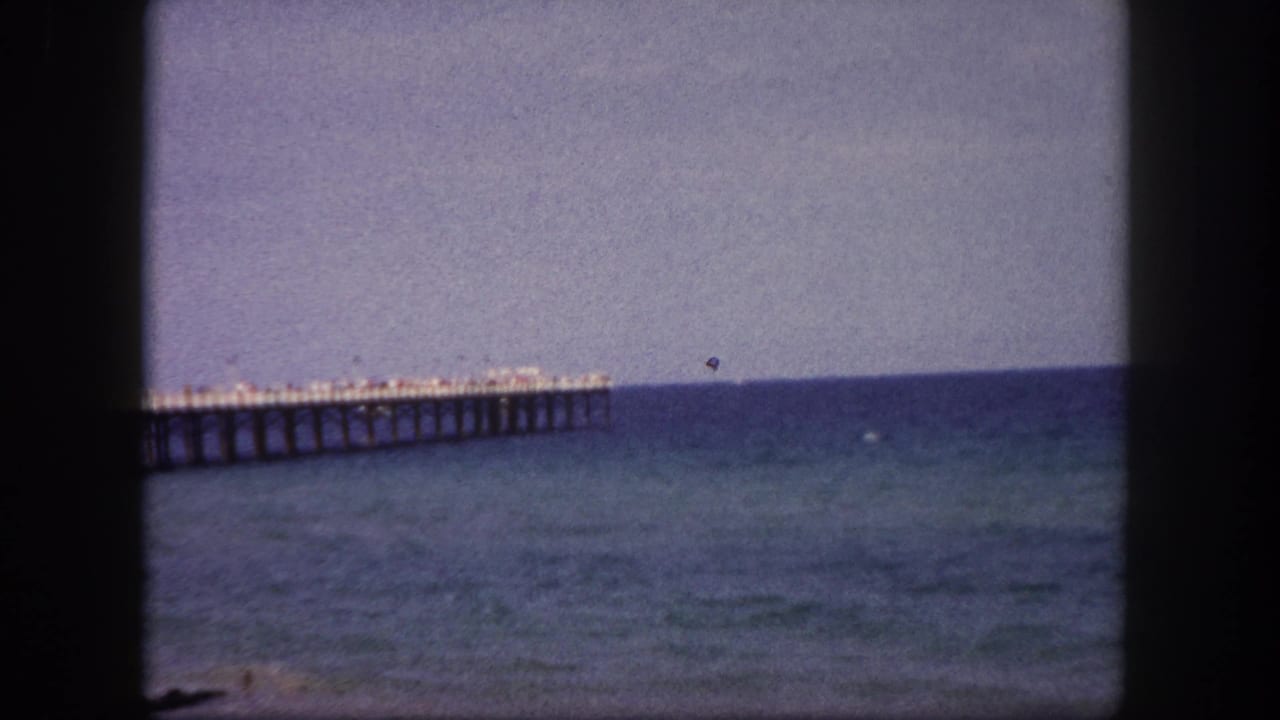 Long pier extending over blue-green water beneath a hazy sky.