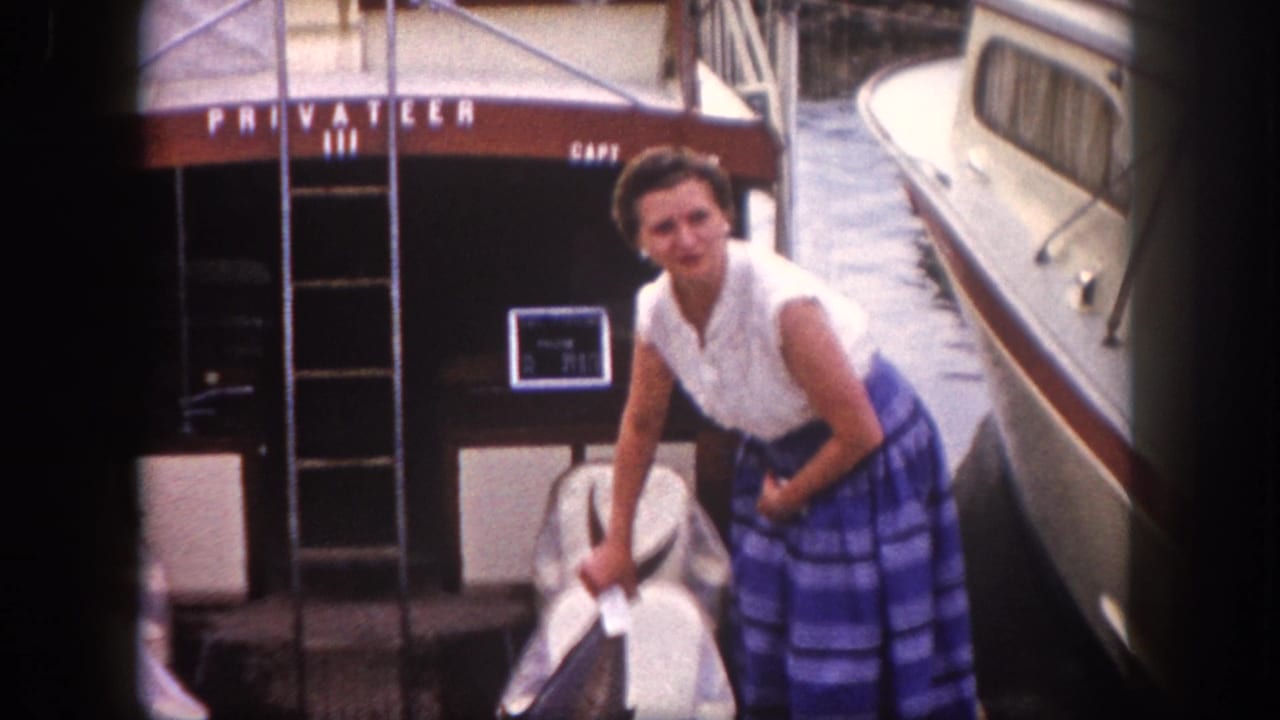 Woman poses with large fish beside the vessel PRIVATEER III at a marina dock, circa 1960, possibly Tampa, Florida.