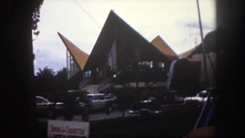 Repeat view of angular mid-century building at what appears to be a Tampa, Florida marina area circa 1960; 'Open 4 Charter' and additional partially legible sign text visible with vintage cars in foreground.