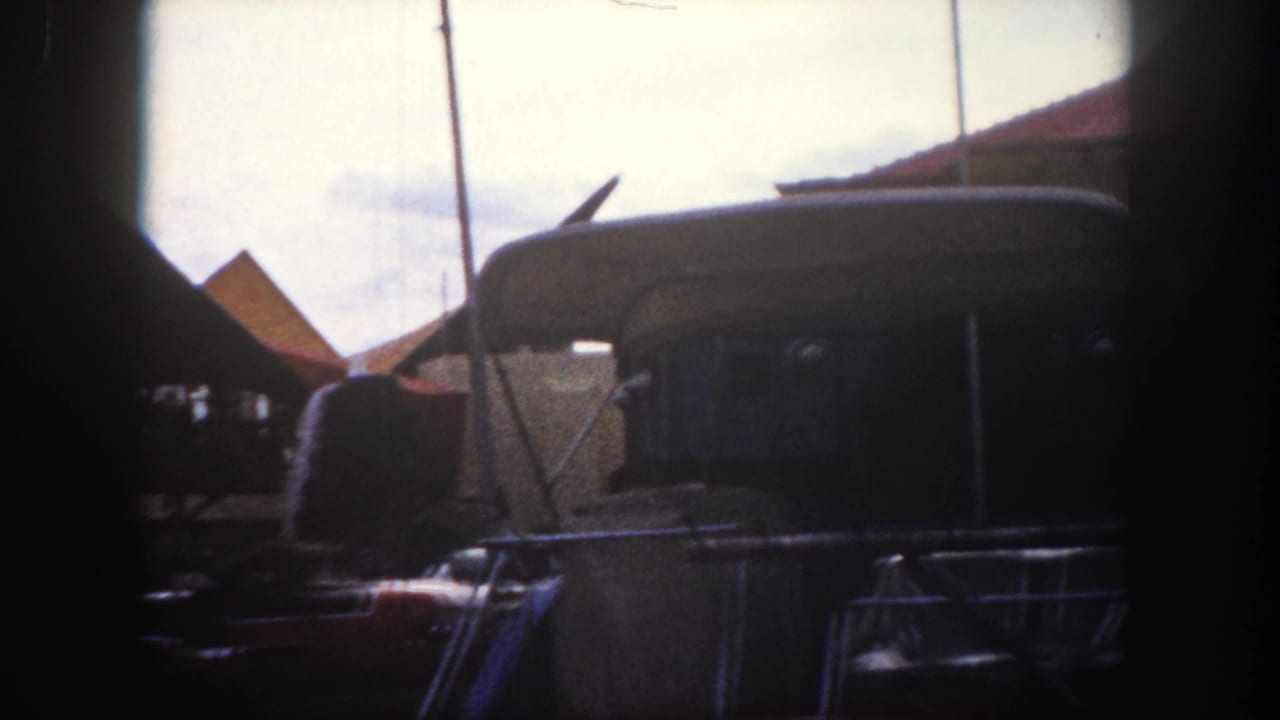 Continuation of the angular commercial canopy streetscape with period American automobiles and a large dark vehicle, Tampa, Florida, circa 1960, 8mm color film.