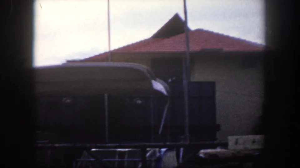 Low-rise building with red clay tile hip roof and palm trees consistent with Florida vernacular architecture, Tampa area, circa 1960, 8mm color film.