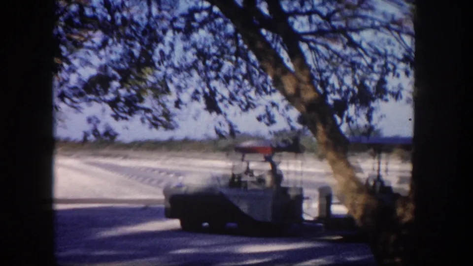 Small tourist tram or open vehicle on a Florida road, circa 1960, with a large shade tree in the foreground and open sky above