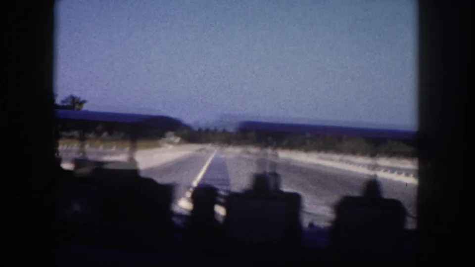 Florida highway shot from inside a moving car, circa 1960, with a flat horizon, minimal roadside vegetation, and bright open sky