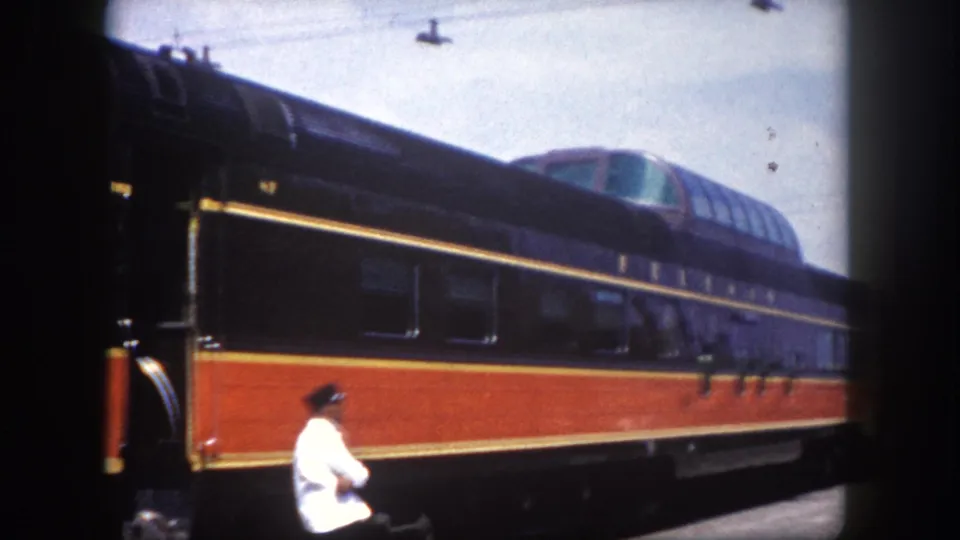 8mm color footage frame of a traveler walking on a station platform beside a dome-car passenger train, Tampa, Florida, circa 1960.