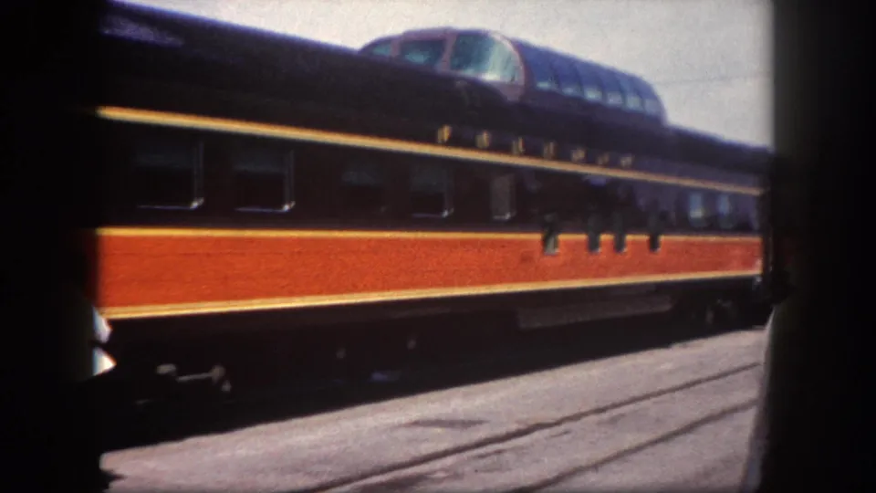 8mm close-up of a dome observation car at Tampa station, circa 1960; glass dome, dark blue upper body, red-orange lower body, and gold pinstripe clearly visible.