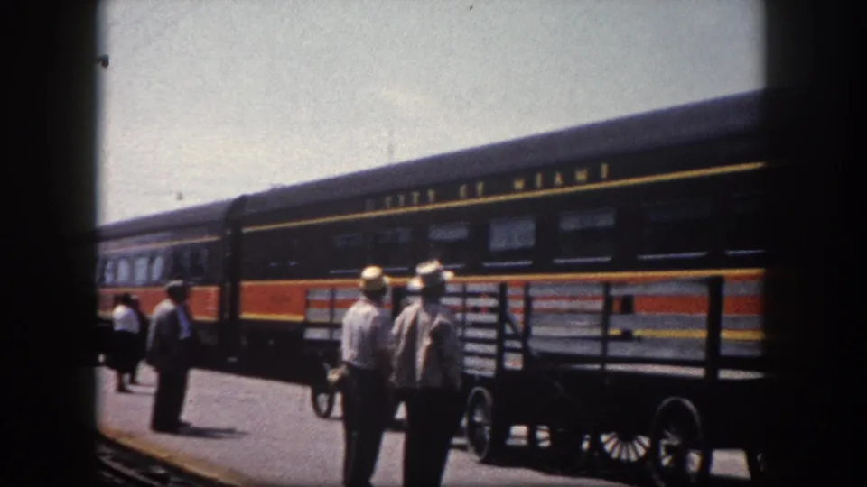 1960 Florida station: platform workers in straw hats with the City of Miami passenger train at the platform and a baggage handcart nearby.