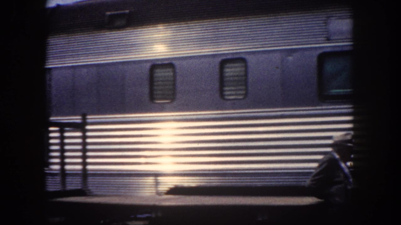 Mid-century stainless steel streamliner passenger car at Tampa station, c. 1960; sunlight creates strong specular reflection across ribbed exterior panels.