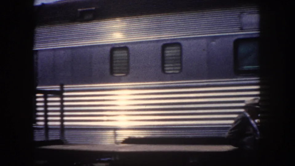 Mid-century stainless steel streamliner passenger car at Tampa station, c. 1960; sunlight creates strong specular reflection across ribbed exterior panels.