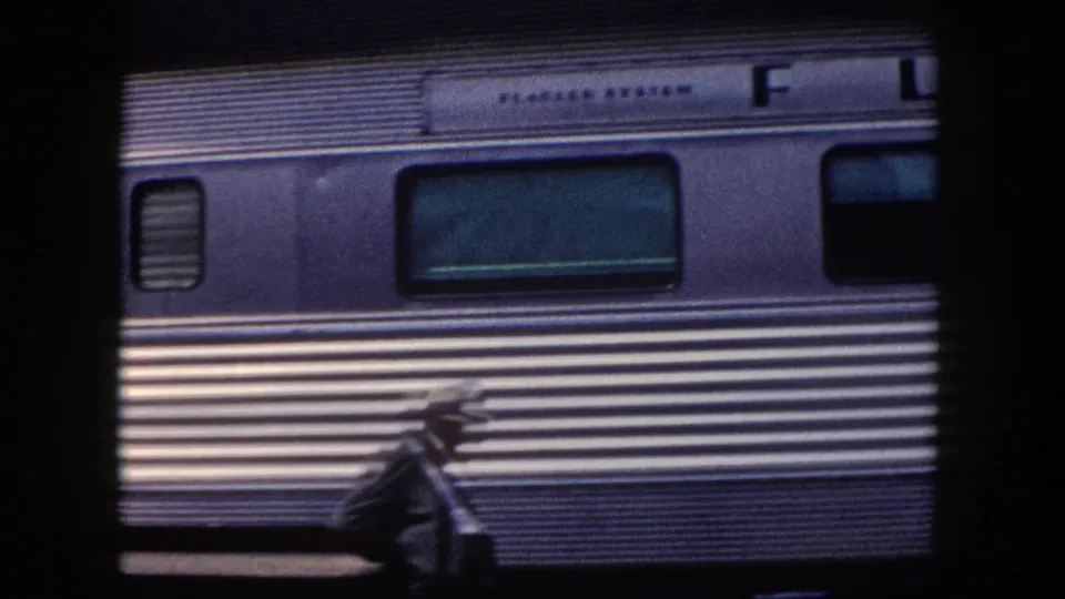 Flagler System passenger car at Tampa station, c. 1960, showing operator lettering and tinted rectangular windows; unidentified figure visible at lower left.