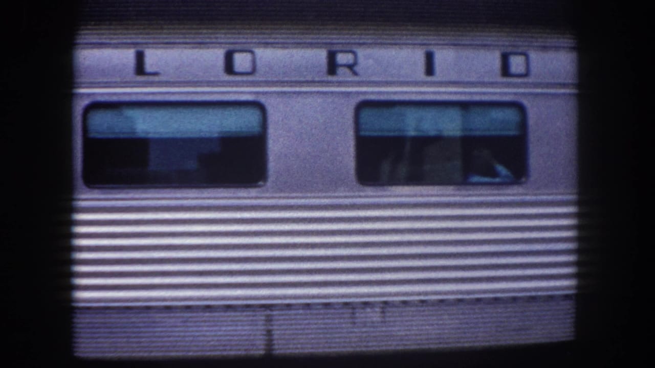 1960 Tampa area: close-up of stainless-steel passenger railcar side bearing partial 'FLORIDA' car name, shot on 8mm film with characteristic grain and blue cast.