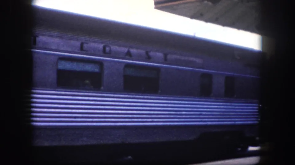 1960 Tampa area: railcar side with 'COAST' (completing 'EAST COAST') and 'BUNNELL' nameplates; overexposed upper-right corner is typical of 8mm film panning a bright sky.