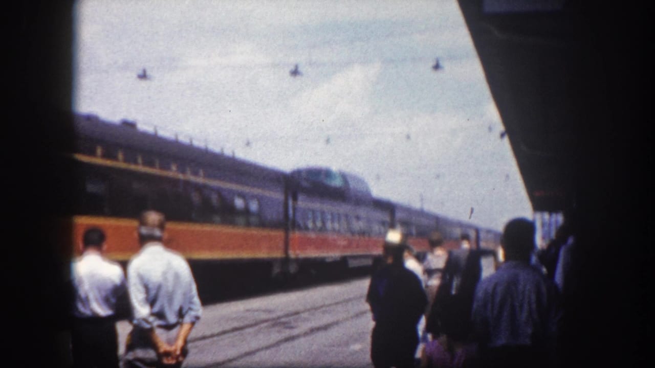 Passengers on a Tampa, Florida station platform face an arriving two-tone passenger train, circa 1960, shot on 8mm film.