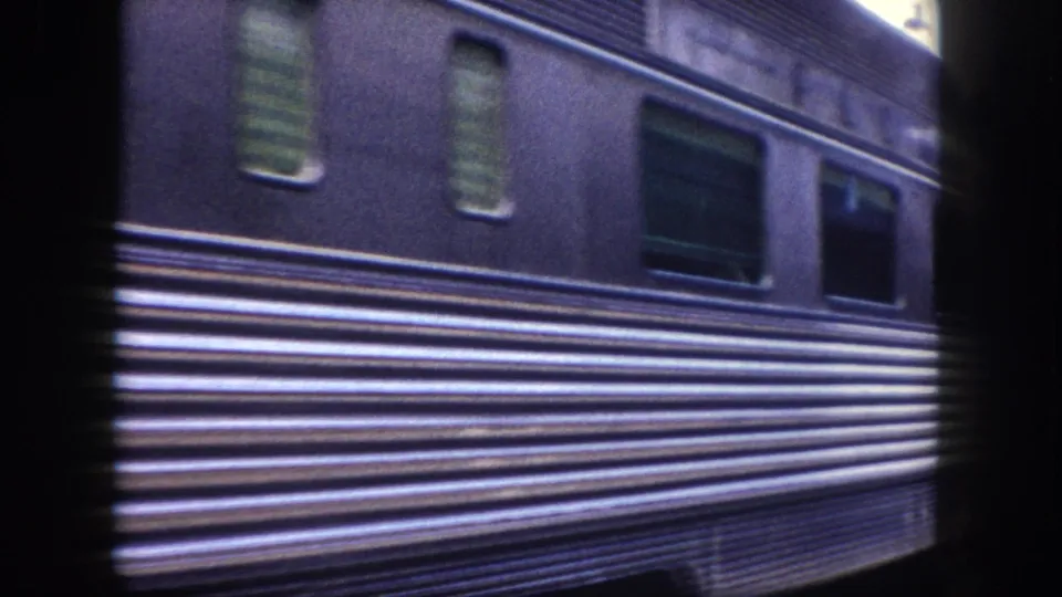 Detail of a dark blue ribbed streamliner passenger car exterior showing horizontal ribbing and windows, circa 1960, 8mm home movie