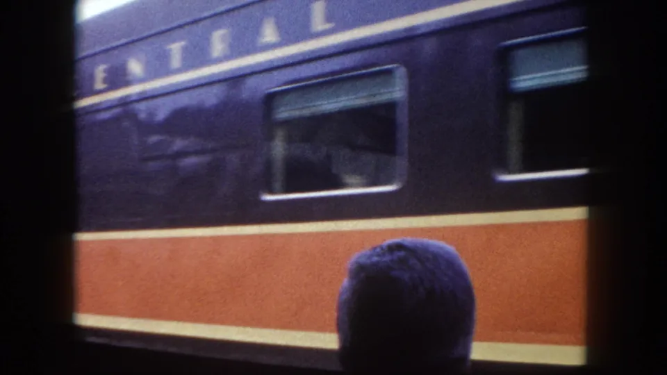 8mm home movie frame showing a dark navy and orange passenger car bearing partial 'CENTRAL' railroad lettering, shot from platform level in Tampa, Florida, circa 1960.