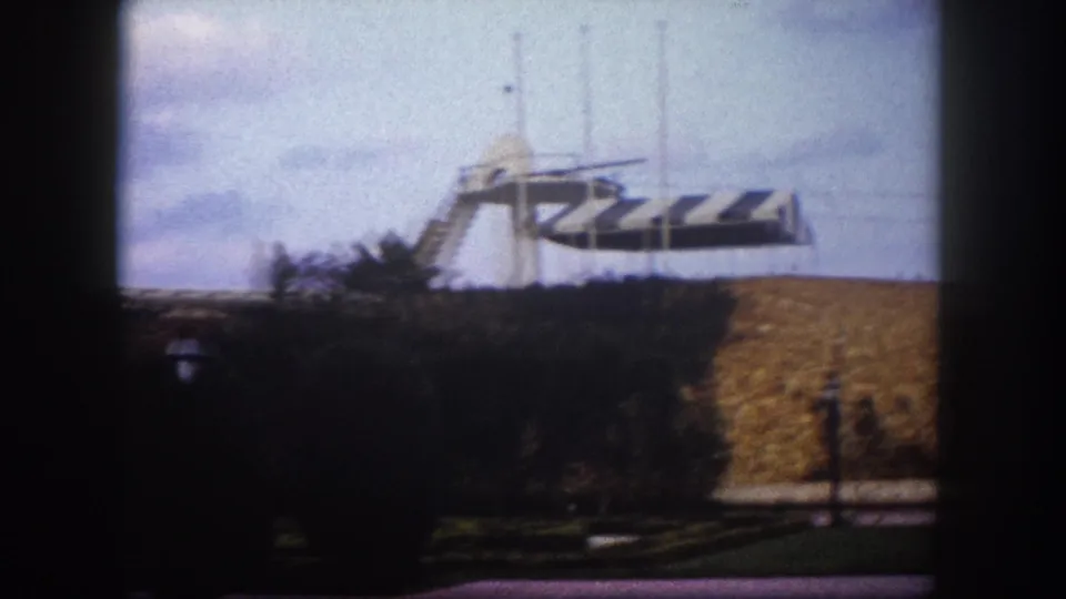 Public square, Tampa, Florida, circa 1960 — striped canopy, flagpoles, and a low modernist stone masonry structure visible during a rightward camera pan.