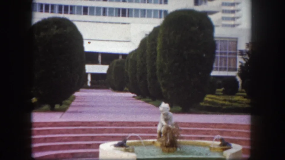 8mm frame circa 1960 showing a formal garden fountain and pink-tiled stepped pathway at what appears to be a Florida resort or civic property, Tampa area.