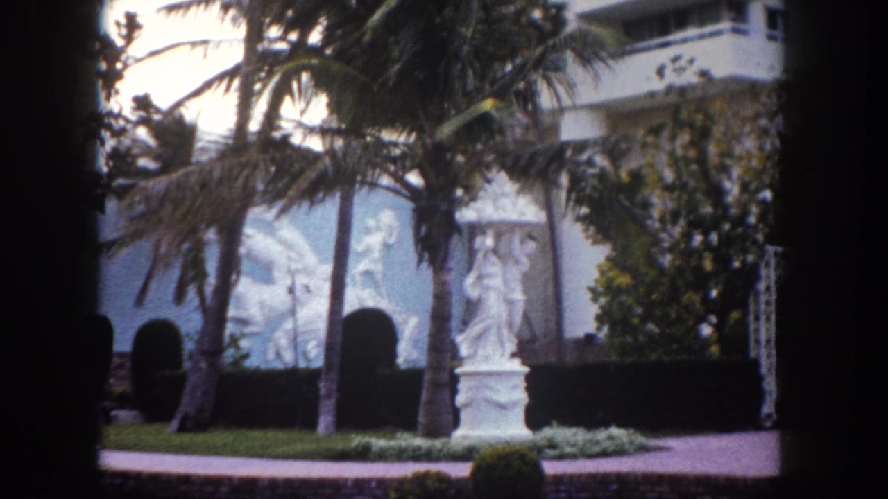 8mm frame circa 1960 showing a white classical garden statue and ornamental relief wall panel at what appears to be a Tampa, Florida resort garden.