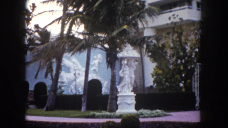 8mm frame circa 1960 showing a white classical garden statue and ornamental relief wall panel at what appears to be a Tampa, Florida resort garden.