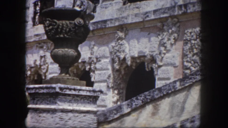 Two ornate carved stone urns atop rough pedestals flank a heavily decorated stone relief wall with steps, Tampa Florida area estate, circa 1960 8mm footage.