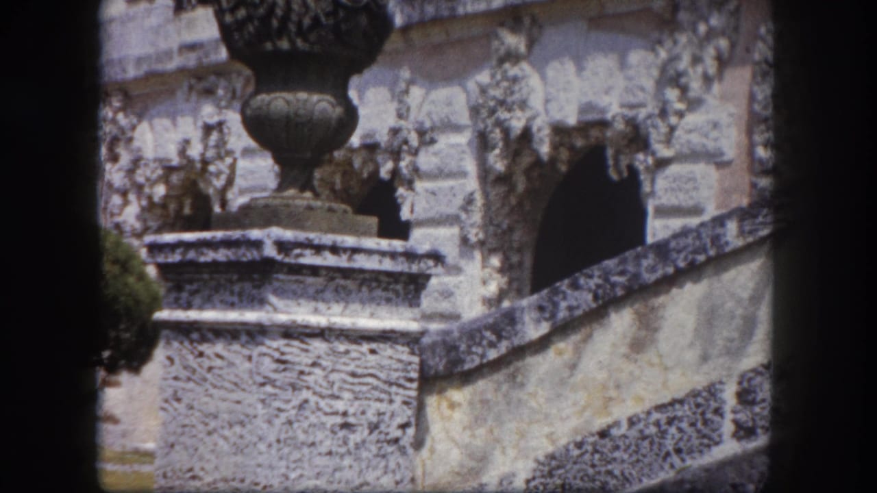 Close-up of a carved stone urn on a rough pedestal with detailed relief stonework behind, Tampa Florida area estate, circa 1960 8mm footage.