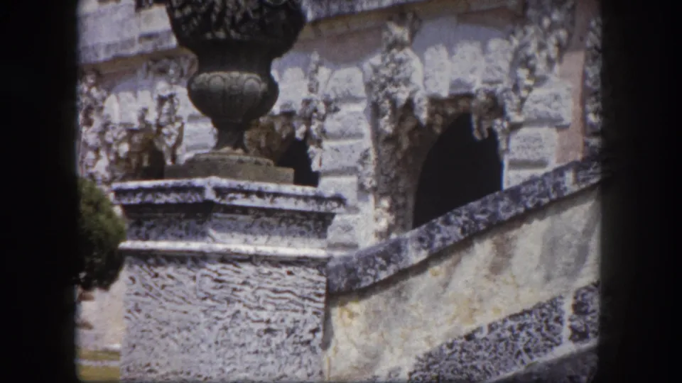 Close-up of a carved stone urn on a rough pedestal with detailed relief stonework behind, Tampa Florida area estate, circa 1960 8mm footage.