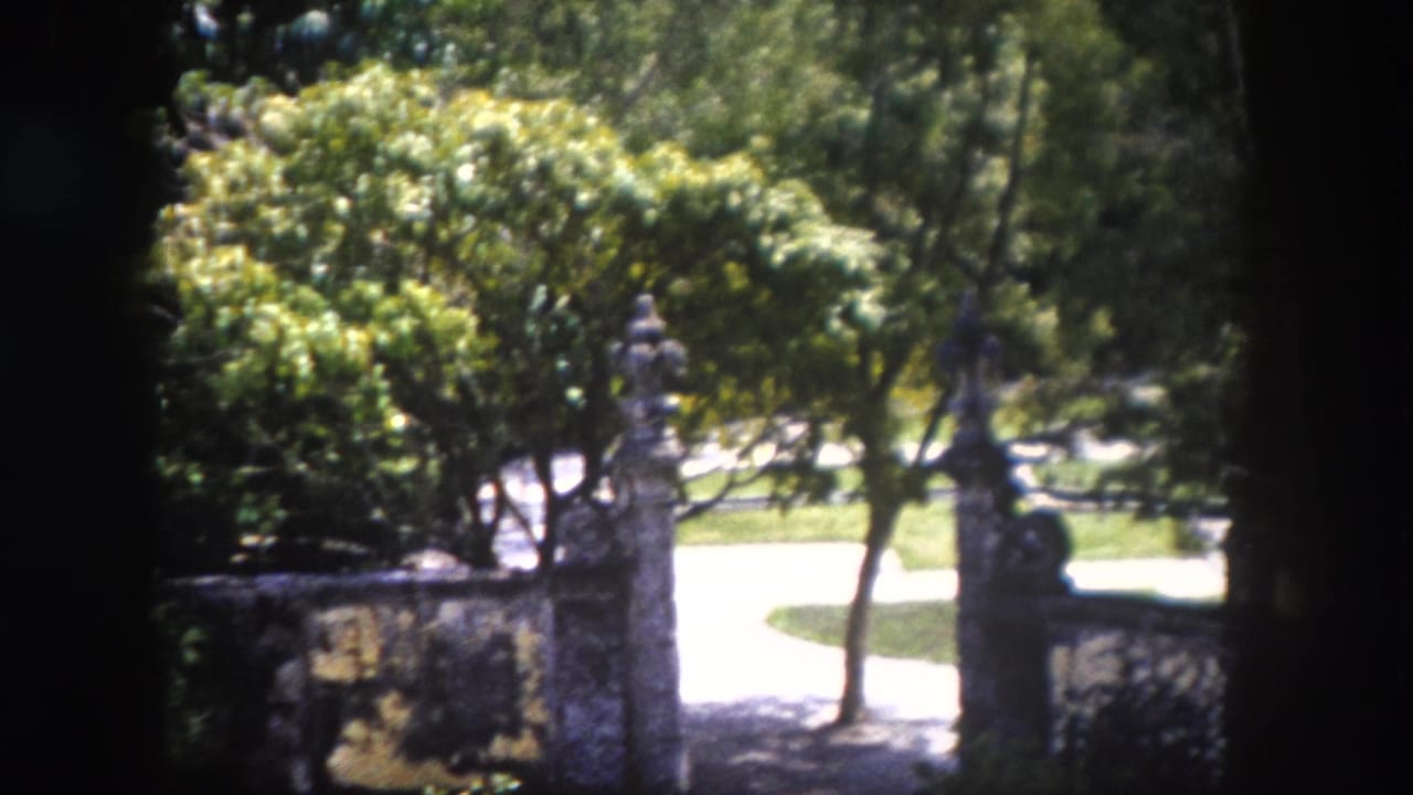 1960 8mm home movie frame of the same formal garden pond and stone gate pillars in Tampa, Florida, from a slightly shifted vantage point.