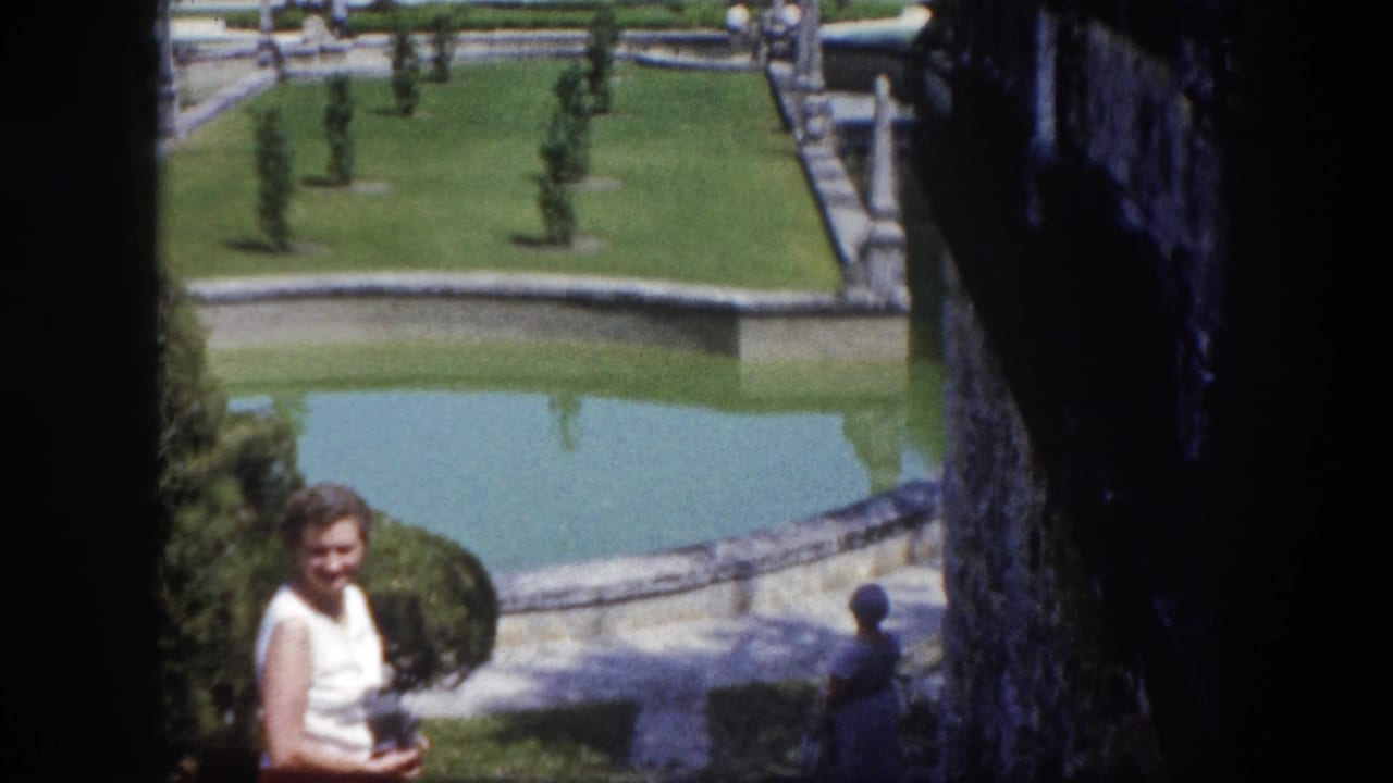 Visitor in white top photographed at greater distance, revealing formal estate garden with reflecting pool and topiary, Tampa, Florida, circa 1960.