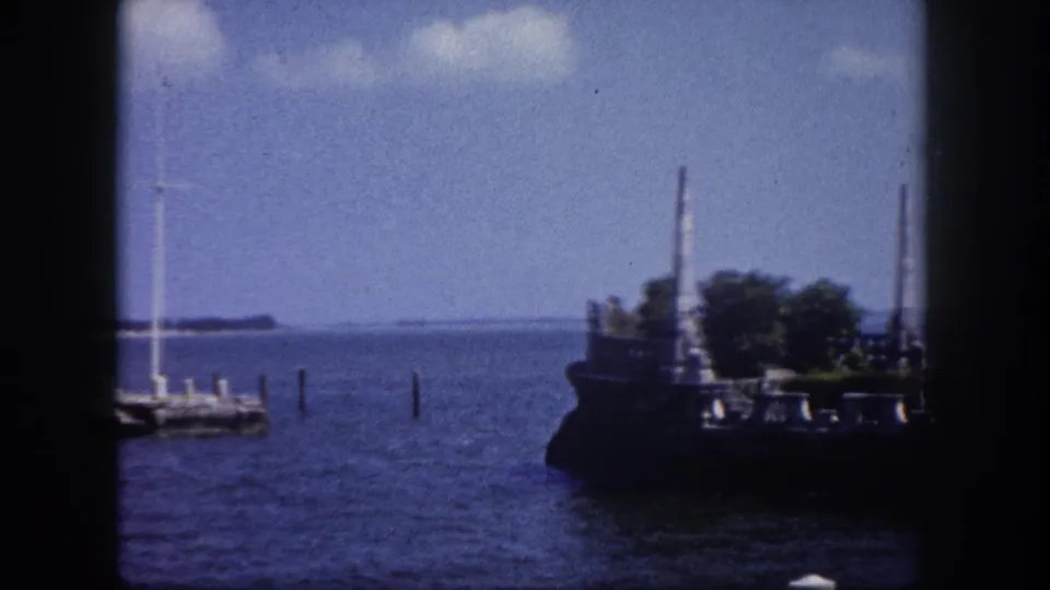 8mm home movie frame circa 1960 showing an ornate stone waterfront structure with decorative pillars and vegetation in the Tampa Bay area, Florida.